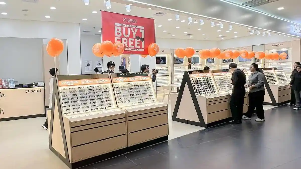 Seseorang memakai kacamata modern dengan latar belakang optik